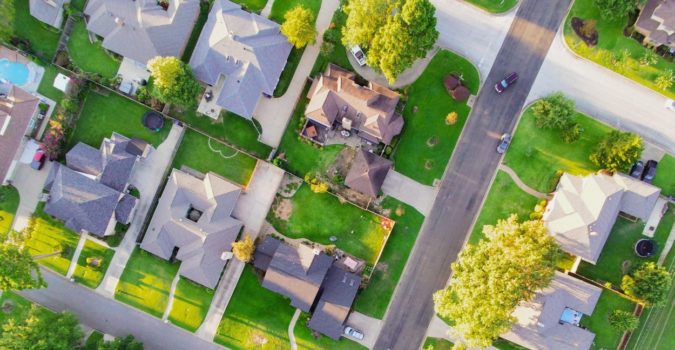 Aerial shot of suburban neighborhood, green grass, and lot boundaries